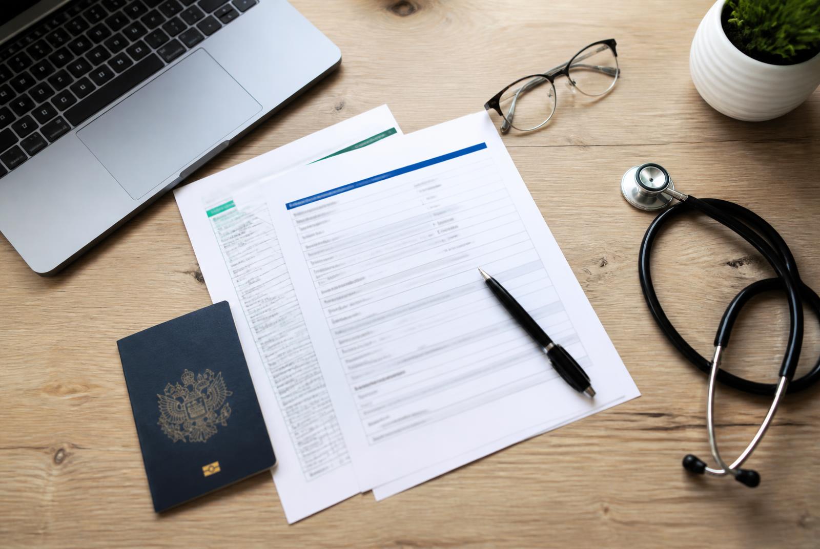 Nursing licence paperwork, passport and stethoscope on a desk